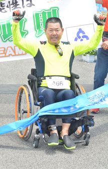 フィニッシュでガッツポーズする赤嶺さん=16日午後、石垣島トライアスロンゴール地点