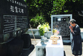 尖閣列島戦時遭難者慰霊碑に手を合わせる慰霊祭参列者=3日午後