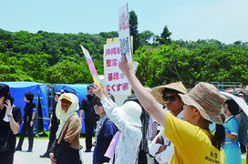 沖縄全戦没者追悼式でプラカードを掲げ、安倍首相に抗議する人たち=23日午後、平和祈念公園