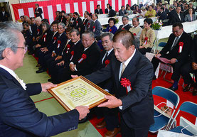与那国町の町制施行70周年式典で外間庁長が73個人3団体を表彰した=2日、離島総合振興センター