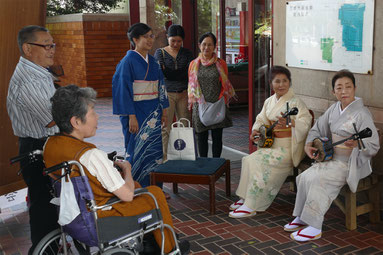 審査を前に会場周辺で三線を演奏する人たち=1日午後、市民会館
