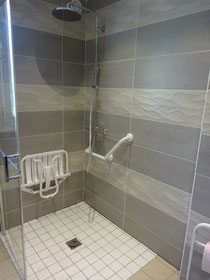 Douche à l'italienne avec siège relevable et barre de maintien