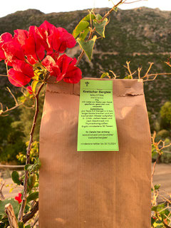 braune Papiertüte mit grünem Etikett vor roter Blume