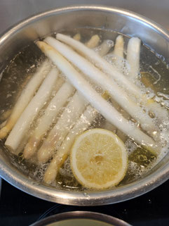 Stangenspargel im Kochtopf mit einer halben Zitrone