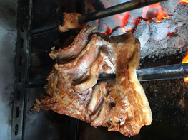 A thick cut of pork belly sizzling on a charcoal grill, with a golden-brown crust forming