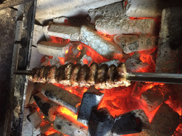 Skewered chicken hearts cooking over glowing charcoal, with a savory char
