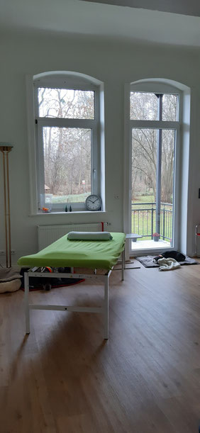 Praxisraum mit Liege und blick auf den Balkon
