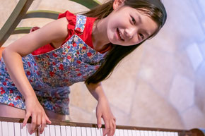 笑顔でピアノを弾く子どもの画像