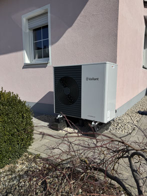 Wärmepumpe vor einem rosanen Einfamilienhaus