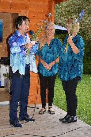 Künstler und Sänger MaLo Magic Blue bedankt sich bei seinen Backgroundsängerinnen, den Firesouls mit Blumen. MaLo-Freiluftvernissage 2025. Private Event.