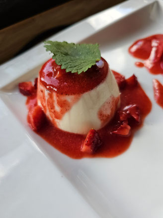 Panna Cotta mit fruchtigem Erdbeerspiegel als Dessert auf dem Teller