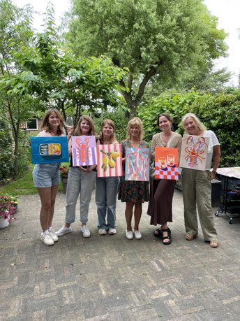 Trots poserende deelnemers met hun schilderijen na een gezellige familie-workshop voor Moederdag bij Daphne Schrijver in Breda.