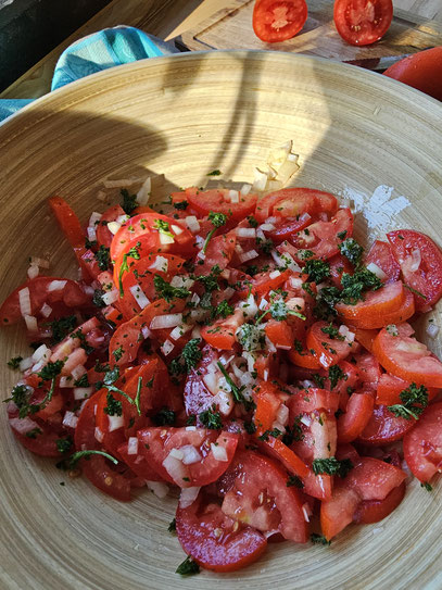 Klassischer Tomatensalat mit frischen Tomaten, Zwiebeln, Petersilie und Essig-Öl-Dressing in einer rustikalen Holzschüssel - einfaches Sommerrezept