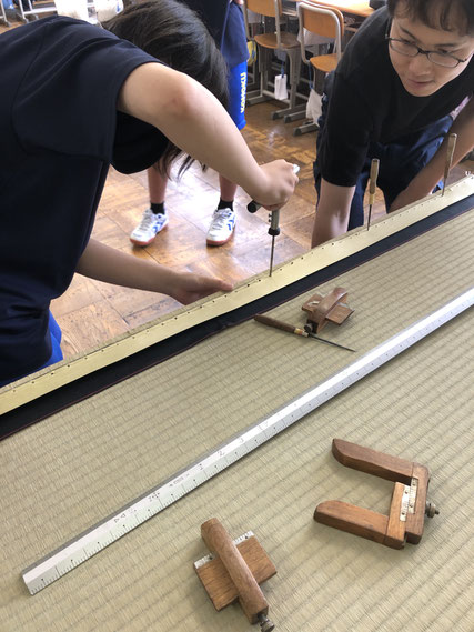 畳の縁部分を手縫いしている中学生の様子。畳専用の道具を使って、縁をしっかり縫い止めている場面。