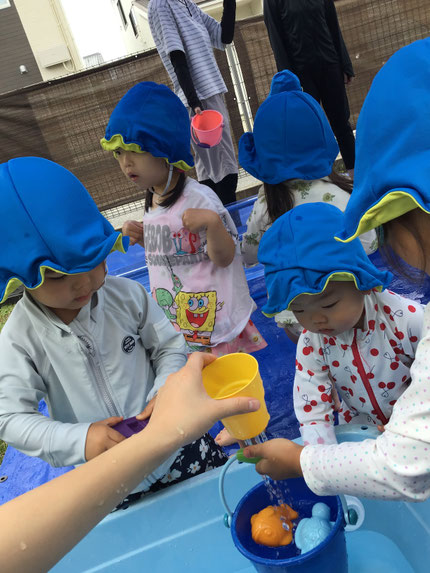 保育者が、穴の空いたコップから水を出すと、「ちょうだい！」「ここ、いれて！」とみんな好きな入れ物に入れてもらったり、自分にも水をかけてもらって大喜びでした！