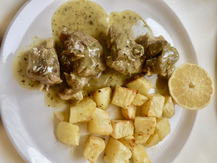 gekochtes Lammfleisch mit Kartoffelwürfeln und Soße auf einem weißen Teller