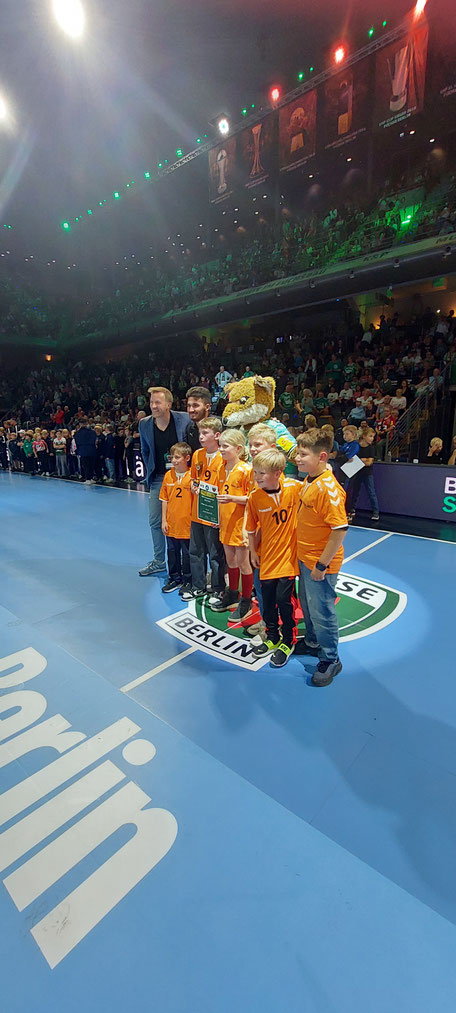 Kinder posieren mit Trainer und Maskottchen.