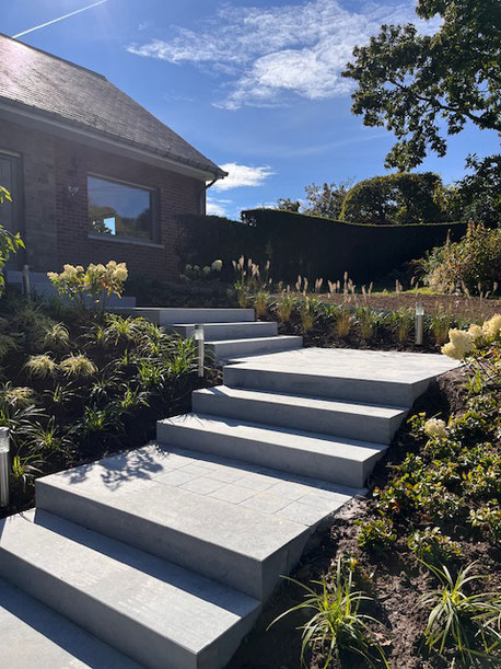 Escalier extérieur design avec plantations harmonieuses, réalisé par Nature et Structure srl, spécialiste en aménagement paysager haut de gamme – pièce maîtresse de l’entrée d’une maison contemporaine.