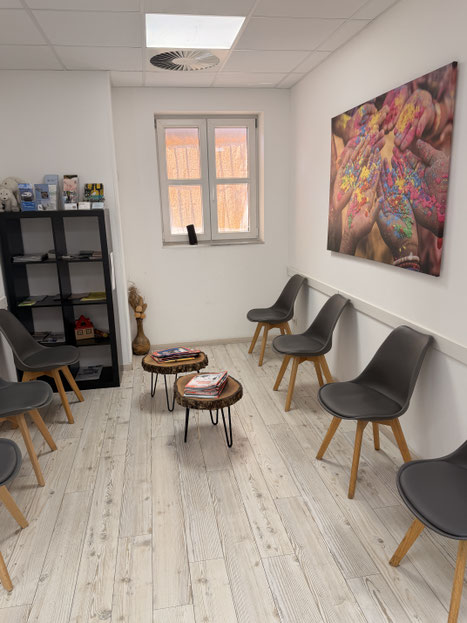 Wartebereich mit Sitzmöglichkeiten und farbigem Wandbild in der Physiotherapiepraxis Ralf Zichel