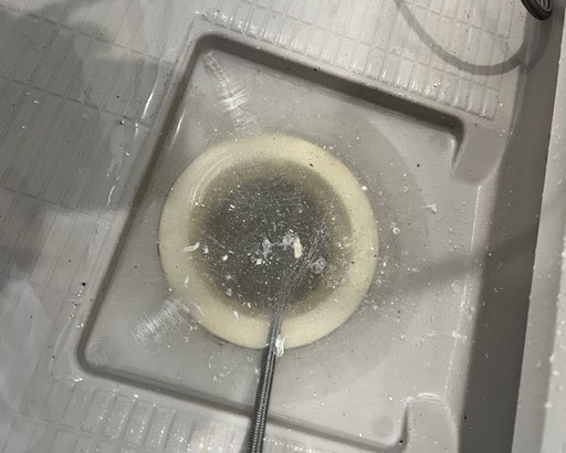 浴室排水口を室内側から高圧洗浄している排水管洗浄作業の写真