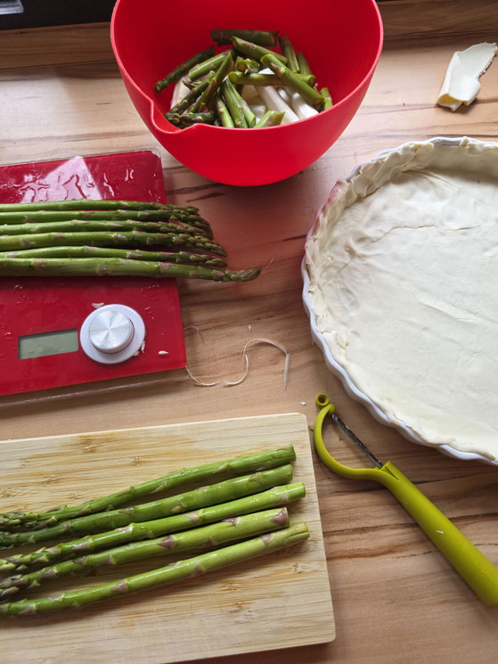 grüner Spargel auf einem Brett bereit zum schneiden, grüne und weiße Spargelstücke in einer Schüssel in Stücke geschnitten für Spargel Quiche