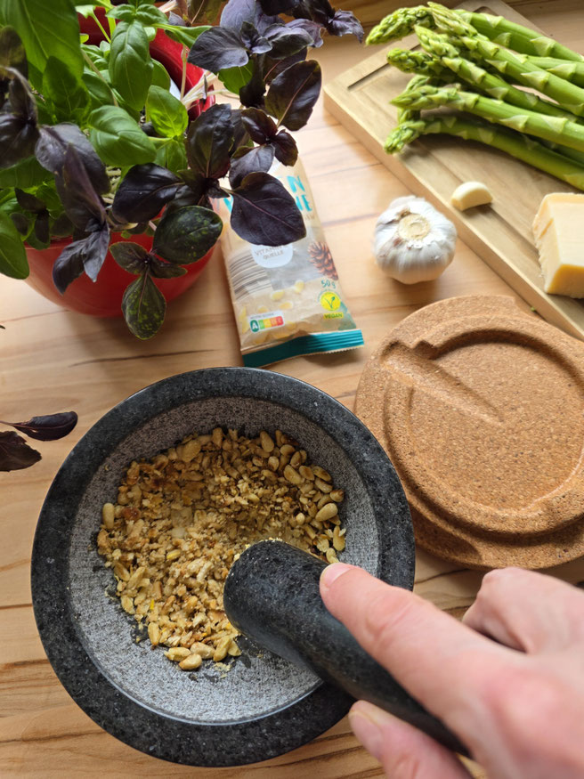 Pinienkerne im Granitmörser zerstoßen für grünes Spargelpesto