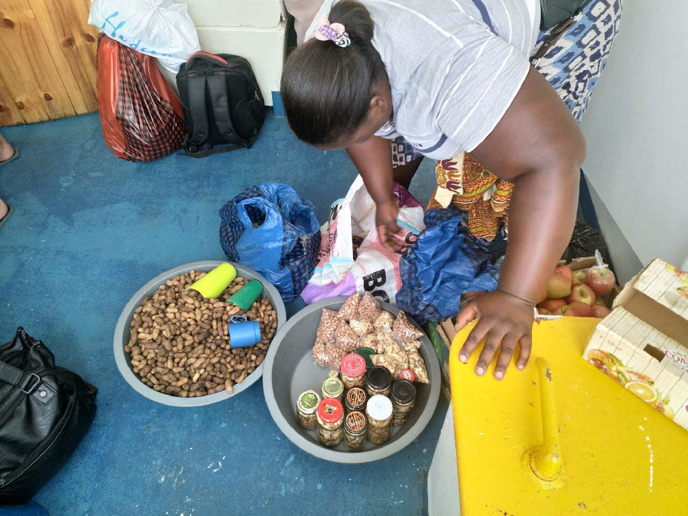 Eine Frau bereitet gekochte Erdnüsse, getrocknete Erd- und Cashewnüsse und Äpfel aus Südafrika für den späteren Verkauf vor.