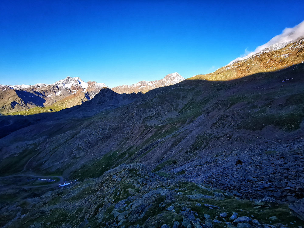 Der Abstiegsweg liegt noch im Schatten der hohen Berge