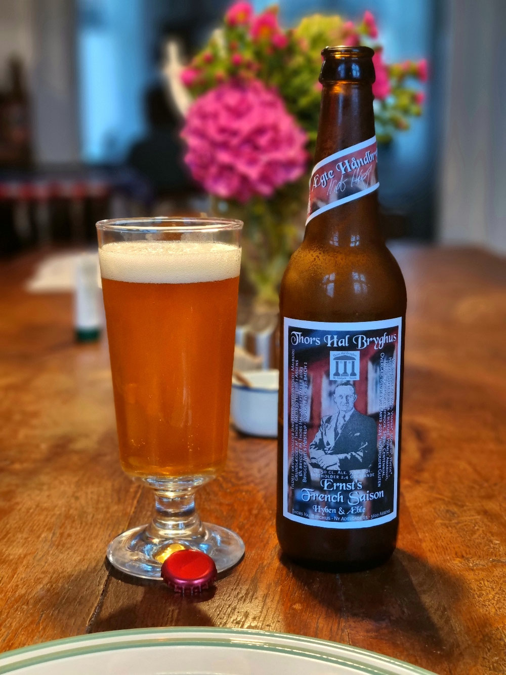 NYHED - Opskrift nr. 23. Ernst's French Saison brygget med hyben og æbler. "J. Ernst's Sølvvarefabrik" Østergade 57 har siden 1890 huset både sølvvareproduktion og bolig for familien Ernst. Johan Ernst (1867-1924) udvidede flere omgange. I 1928 overtog sønnen Frederik (1893-1976) både "J. Ernst's sølvvare" og den lejlighed, der vat tilknyttet fabrikken. I 1950erne lukkede fabrikken og Frederik omdannede fabrikslokalerne til at rumme hans enorme samling af interiører og kunst fra hele verden. "French Saison" er en hyldest til Ernst. Ølstilen er også det, der bliver kaldt, Farmhouse, eller gårdøl fra det franske, French Saison er kraftfuld og frugtig Den er godt humlet og tilsat frugt fra den danske sensommer i form af "Hyben & Æbler" En øl Frederik Ernst ville værdsætte. ",ER DET SMUKT, SÅ MÅ JEG EJE DET" ALK. 7,0% Vol.