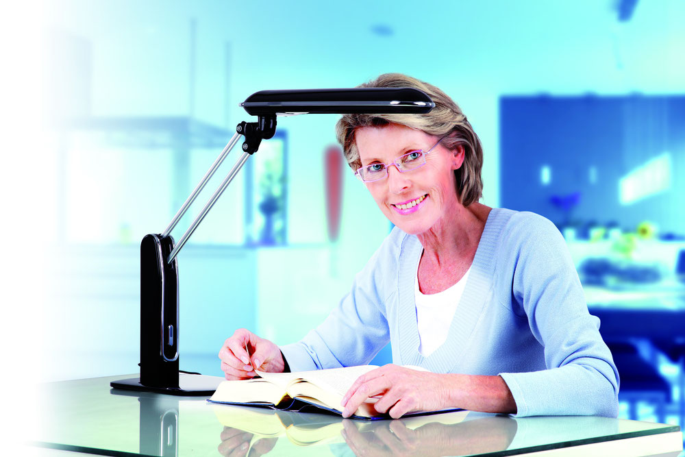 Frau beim Lesen unter der Schreibtischleuchte von LowVision