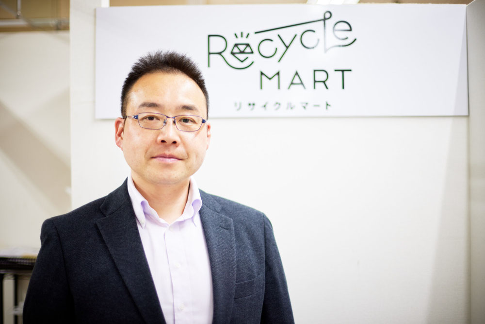 リサイクルマート桐生の看板前に立つオモイヲの代表