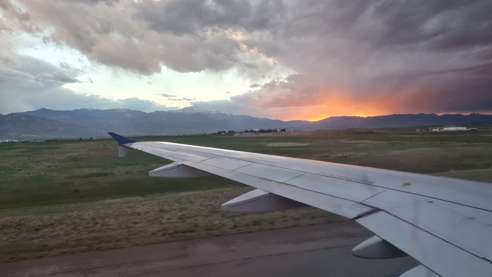 Zwischenlandung in Denver und Weiterflug nach Colorado Springs mit Sonnenuntergang im Westen und den Rand der Rocky Mountains im Hintergrund