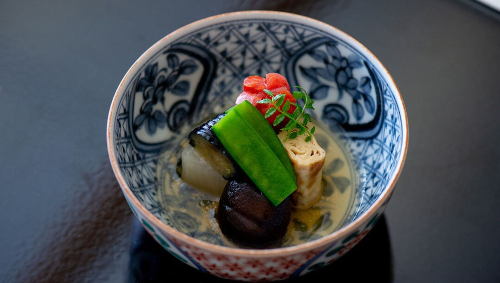 Japanese kaiseki simmered dish with seasonal vegetables in a ceramic bowl.