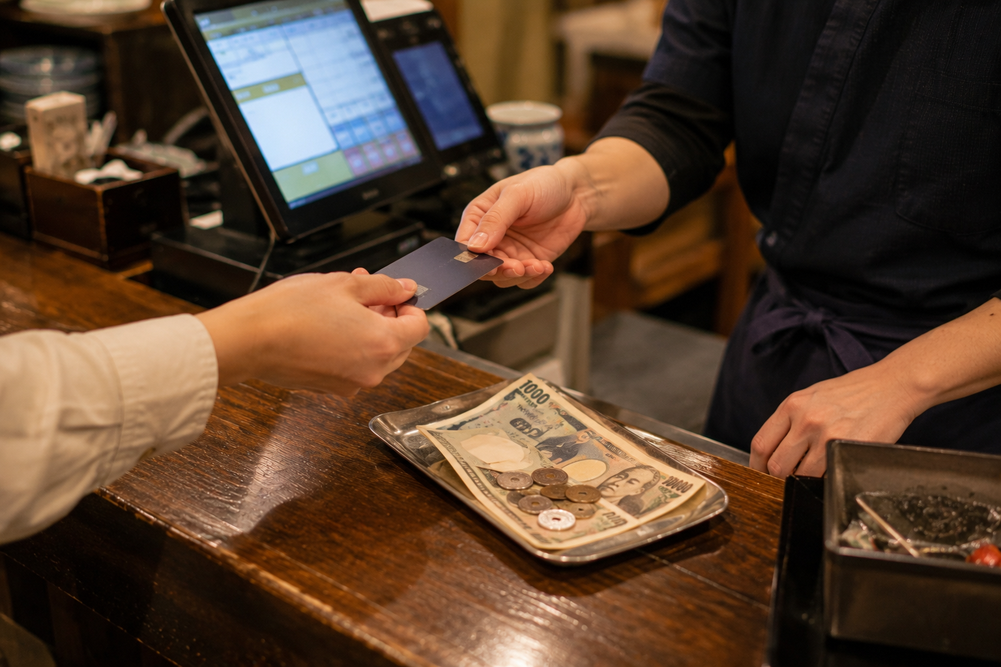 Payment moment at a Japanese restaurant counter with cash and credit card visible.