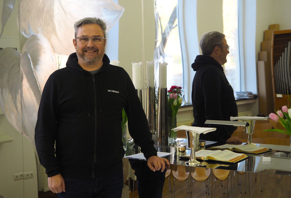 Sune Haubek ist Pastor an der dänische Benediktekirchen in Hamburg – hier fotografiert im Altarraum des Gotteshauses. Foto: Christoph Schumann, 2025