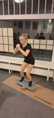 Friederike steht auf einem Balance Board in konzentrierter Pose.