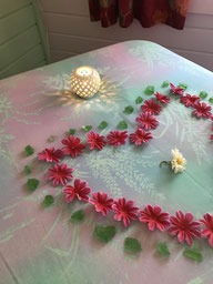 Photo du haut de la table de massage décorée avec un coeur de fleurs fuschia bordées de pierre émeraude
