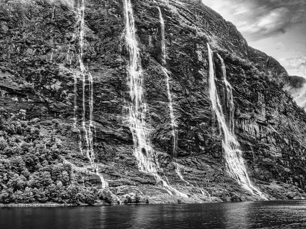 Das Bild zeigt Wasserfälle die sich in einen Fjord erfiessen