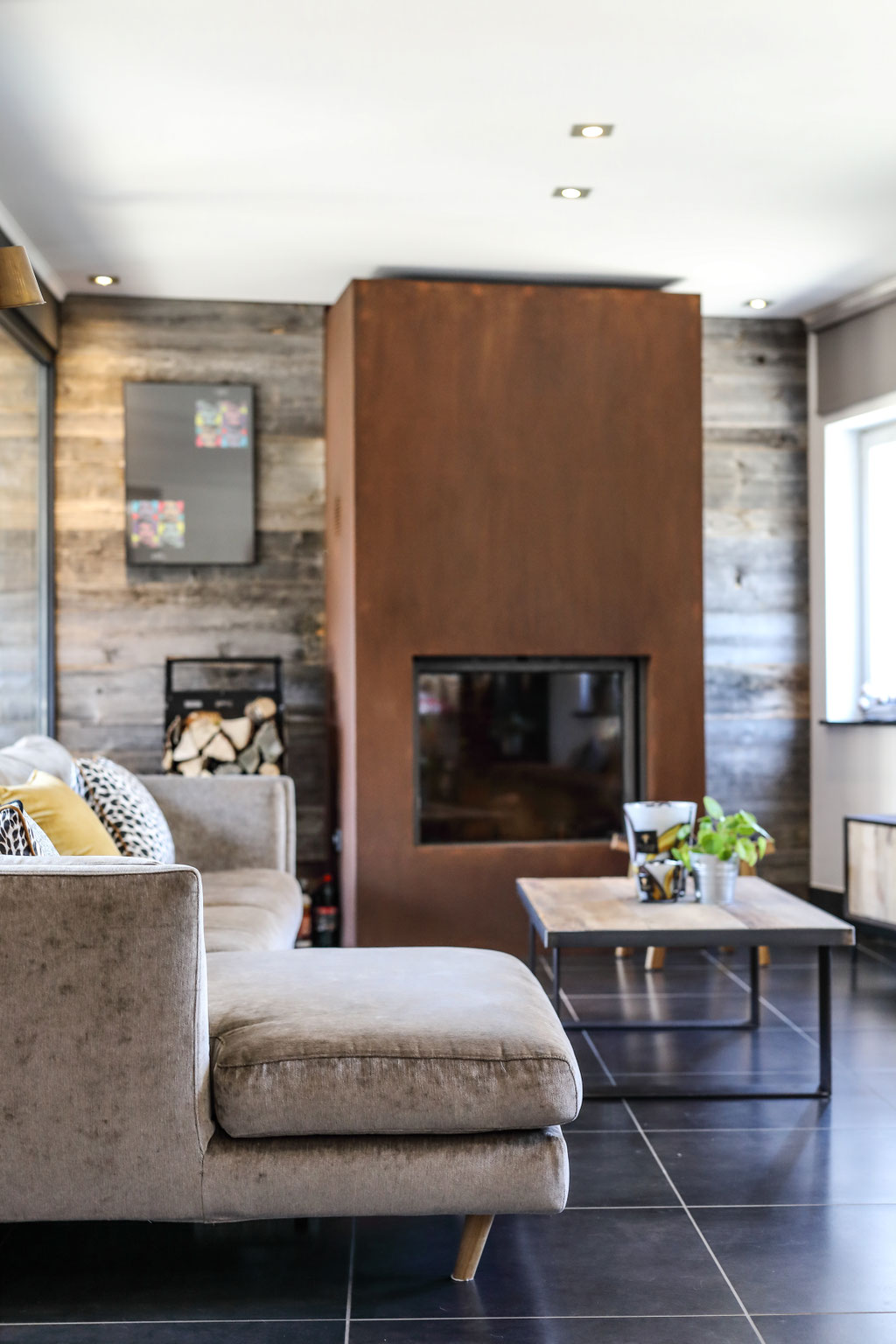 Tablier de cheminée en corten avec en décoration un parement mural en vieux bois de chêne. Catherine Colot Architecte d'intérieur Rochefort