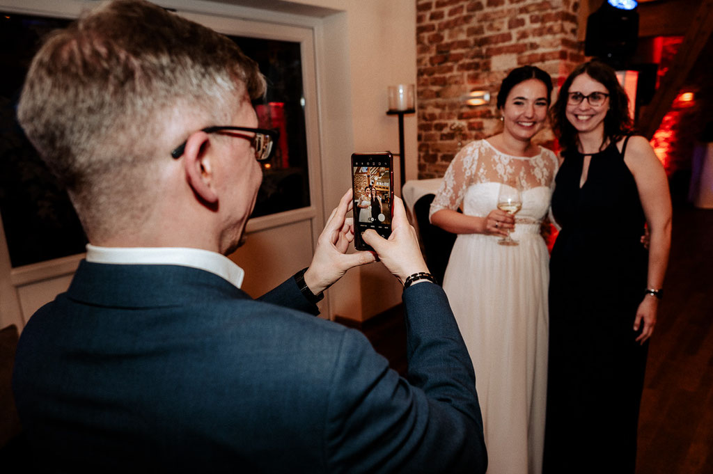 Ein Gast macht ein Handyfoto auf der Hochzeitsfeier.