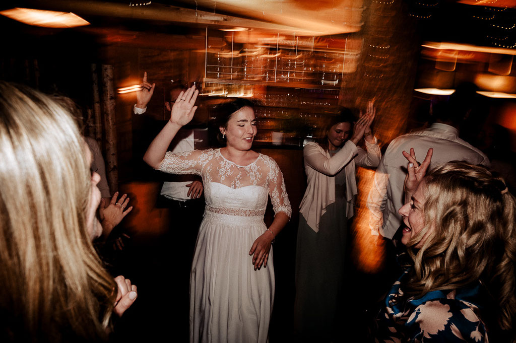 Die Braut tanzt ausgelassen un der Menge. verschwommene Lichter um sie.