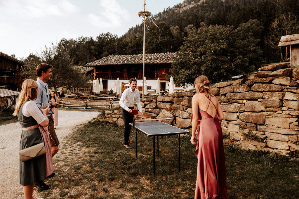 Die Hochzeitsgäste spielen Tischtennis beim Wasmeier Freilichtmuseum am Schliersee. Hochzeitsreportage von Hochzeitsfotograf Andreas Reiter