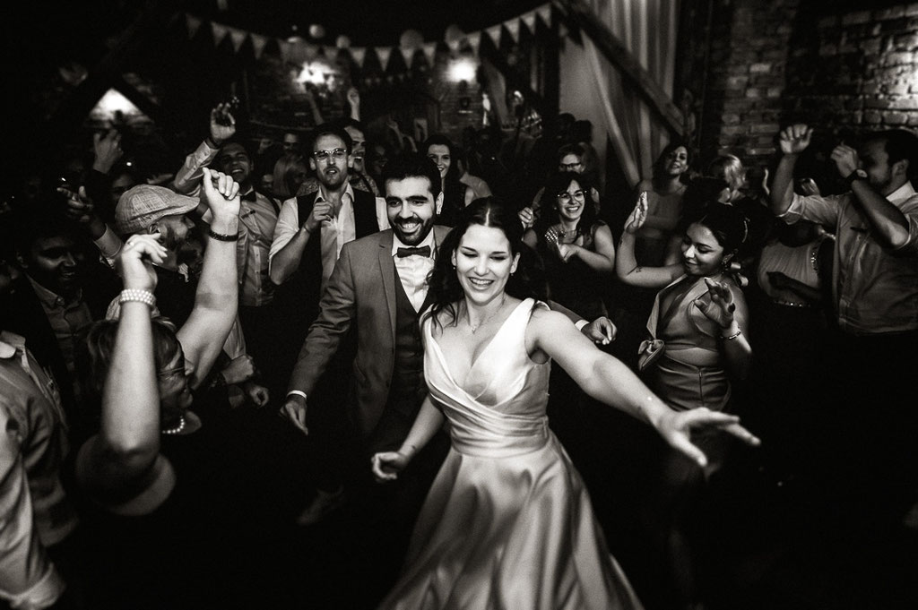 Das Brautpaar zwischen seinen Hochzeitsgästen. Alle tanzen wild.