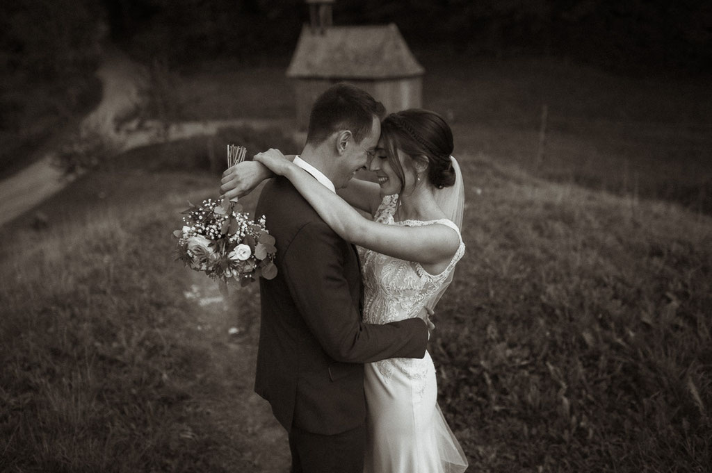 Brautpaarfotos von Hochzeitsfotograf Andreas Reiter, ein Brautpaar steht sich gegenüber Kopf an Kopf und genießt den Moment. 