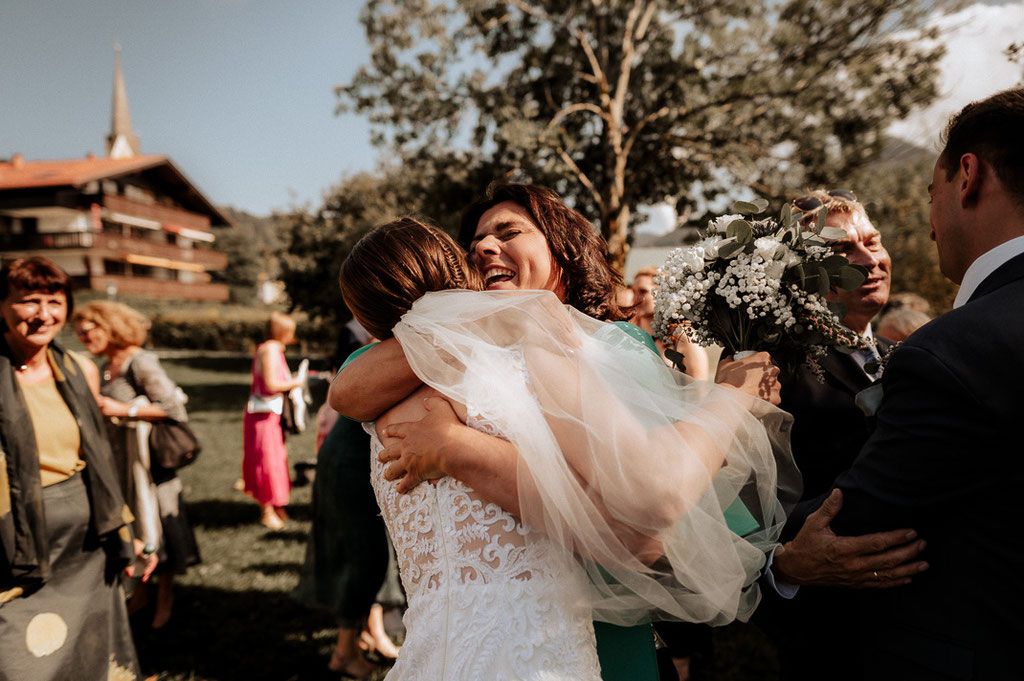 Hochzeitsfotografenpaar am Schliersee.Die Brautmutter umarmt die Braut und gratuliert ihr.