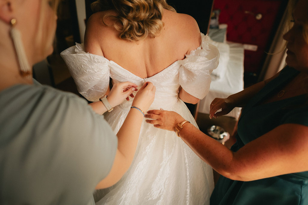 Braut beim Anziehen des Kleides
