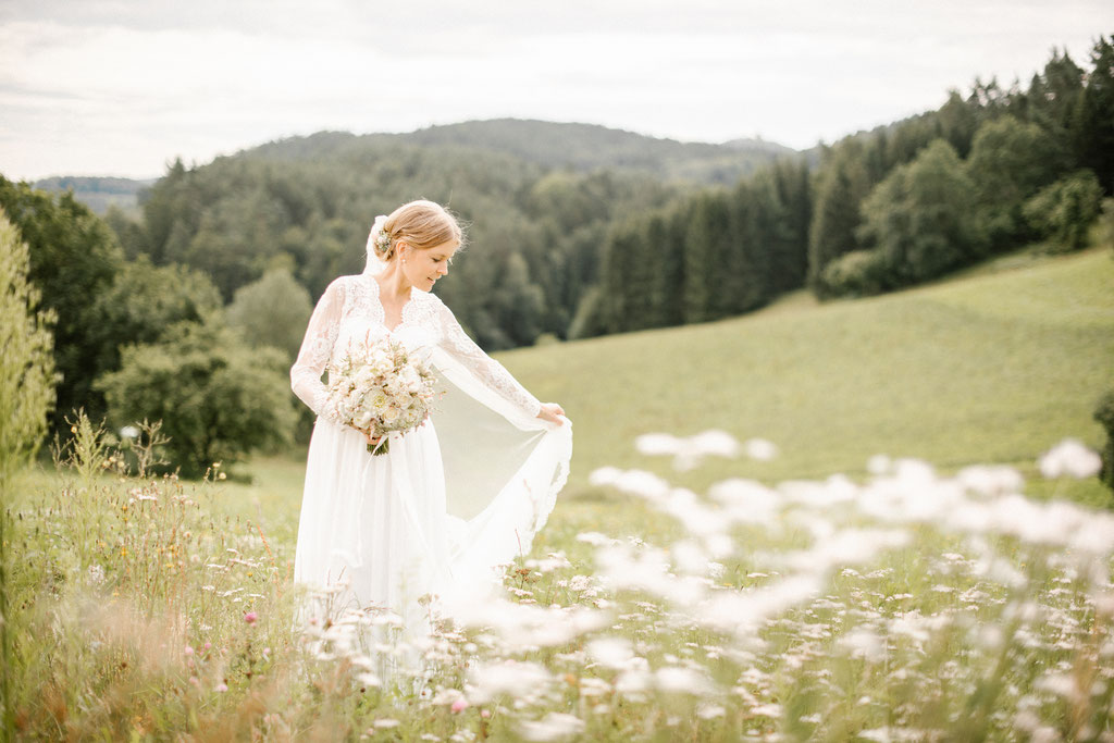 Braut mit Brautkleid in grüner Wiese aufgenommen von einem Hochzeitsfotografen.