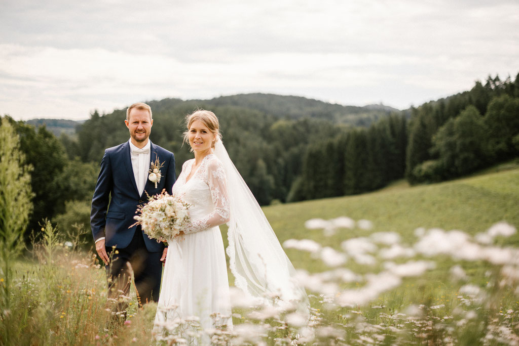 Braut und Bräutigam in grüner Wiese bei ihrer Hochzeit.