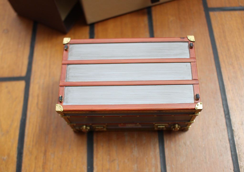 Detailed view of Louis Vuitton 1899 zinc Explorateur mini trunk, faithful reproduction with labels.