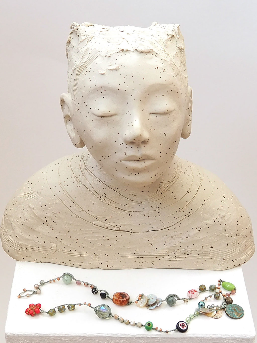 weisser Buddha auf Keramik mit Perlenkette